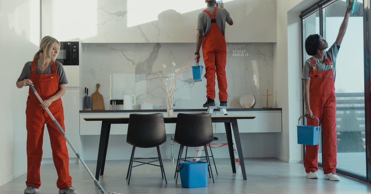 Reinigungsteam in Arbeitskleidung reinigt gemeinsam eine Glasfläche – gutes Onboarding hält neue Reinigungskräfte im Betrieb
